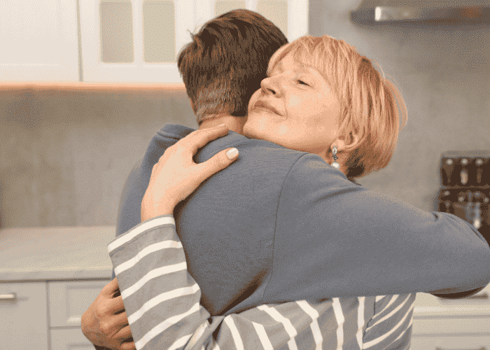 Mom hugging teen son in kitchen smiling after support with parent reviews and testimonials
