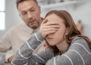 Dad sitting with teen daughter feeling concerned about her mental health and considering touring a residential facility