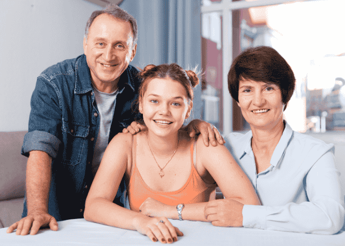 Mom and dad with teen daughter smiling after support with touring a residential facility