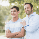 Dad outside with hands on shoulders of teen son smiling after support with red flags when choosing programs