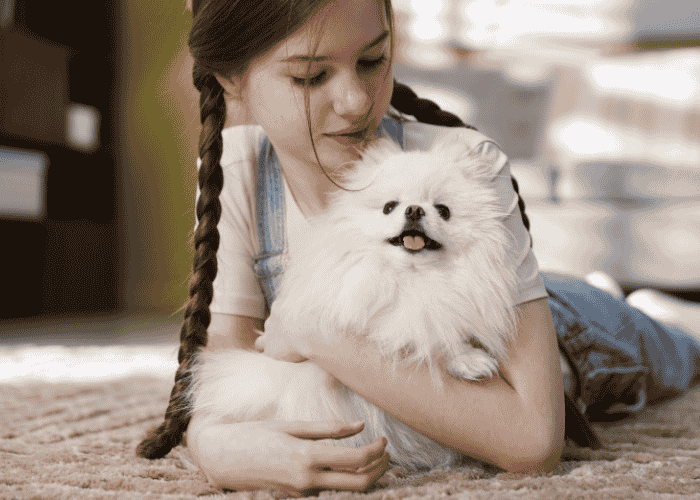 Teen girl laying on floor hugging dog experiencing pet grief