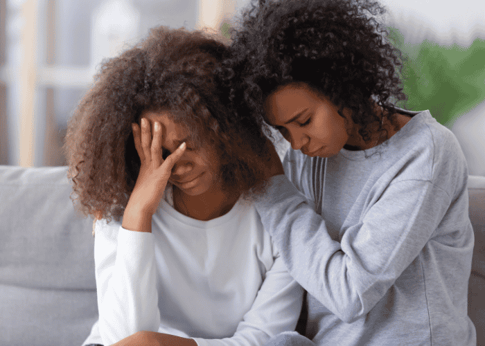 Mom sitting with teen daughter hugging her needing support with raising resilient teens.