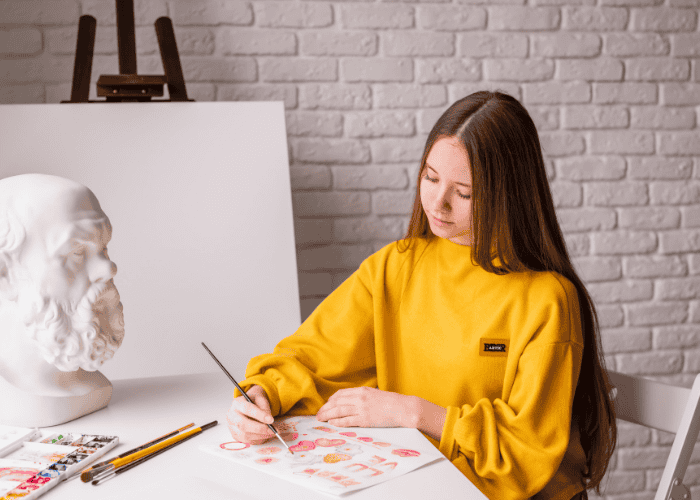 Teen girl drawing in art studio after researching link between creativity and mental health