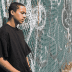 Teen boy leaning against wall outside alone wondering why are teens more connected but also more lonely