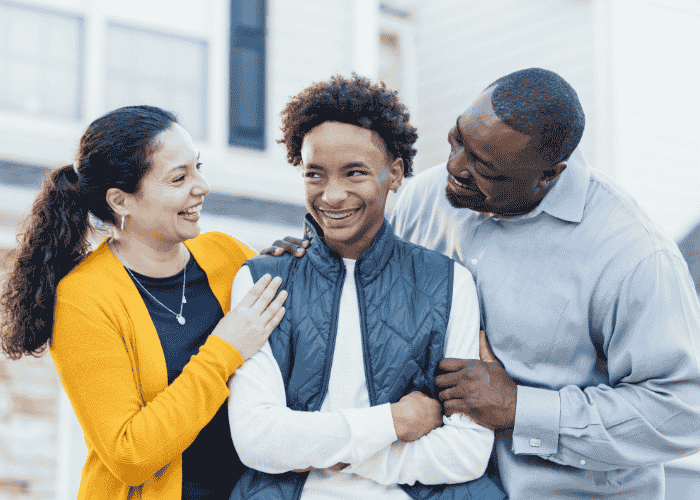 Teenage boy standing outside with his mom and dad smiling after receiving support for shame-based social anxiety