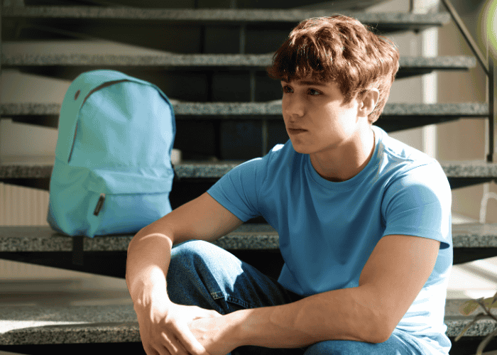 Teen boy sitting on step outside needing support with choosing the right residential program