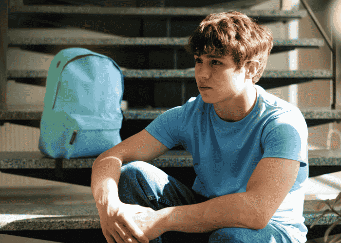 Boy sitting down on school stairs sad because he had no future vision planning