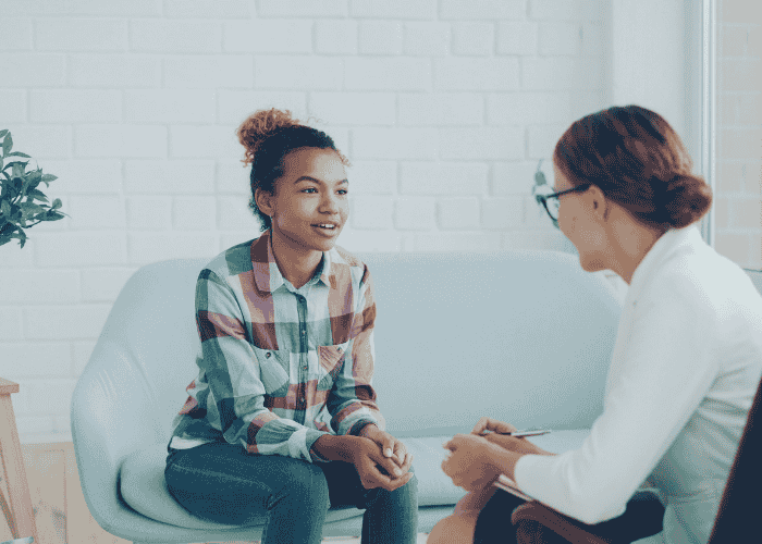 Teenage girl sitting with a therapist talking about gender identity exploration in teens