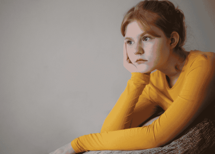 Teenage girl leaning head on hand thinking about their identity and peer acceptance