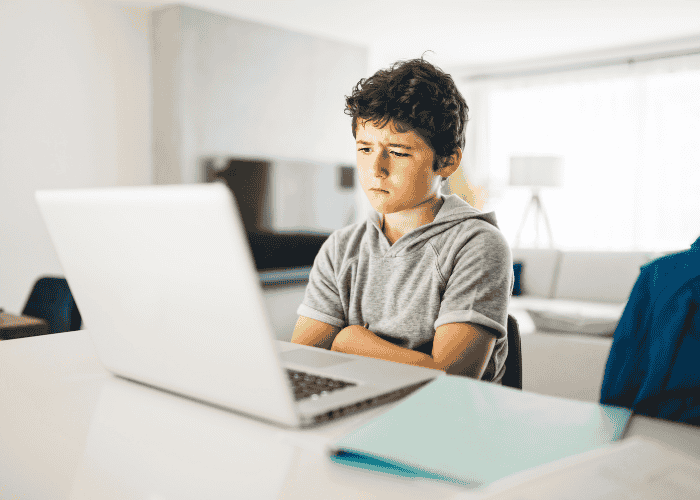 Boy sitting down with a laptop frustrated in need of online high school for teens
