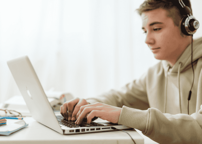 teenage boy sitting at laptop finding home work easy during online high school for teens