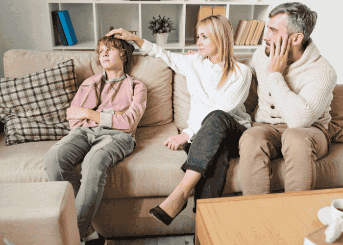 Teenager sitting down frustrated with family about out-of-network insurance