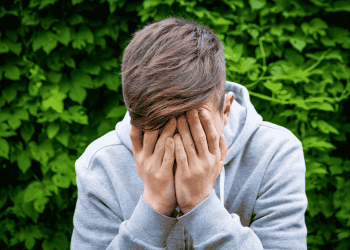 Teenage boy with head in his hands struggling with shame and self-worth in teens