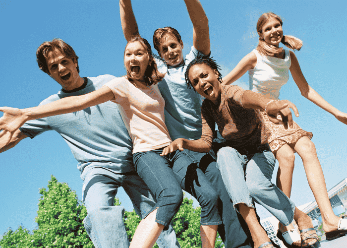 Happy teens jumping in a park because they received treatment for shame and self-worth in teens