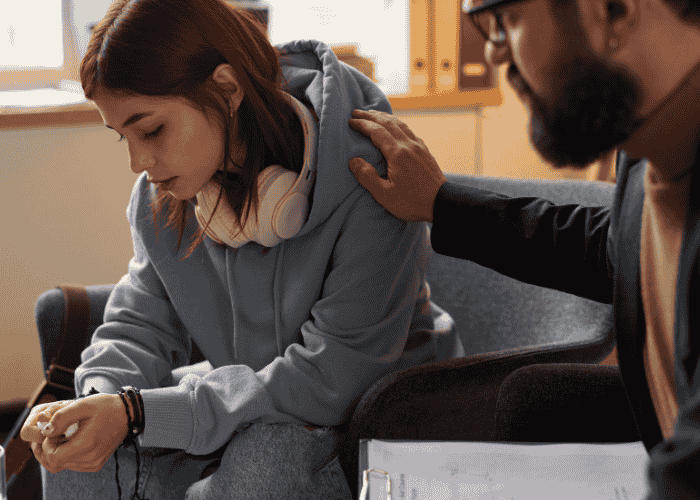 Teenage girl looking sad at the floor, in need of Trauma-Informed Care for Neurodivergent Teens