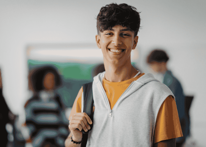 Teen boy in school smiling after support with building confidence after treatment.