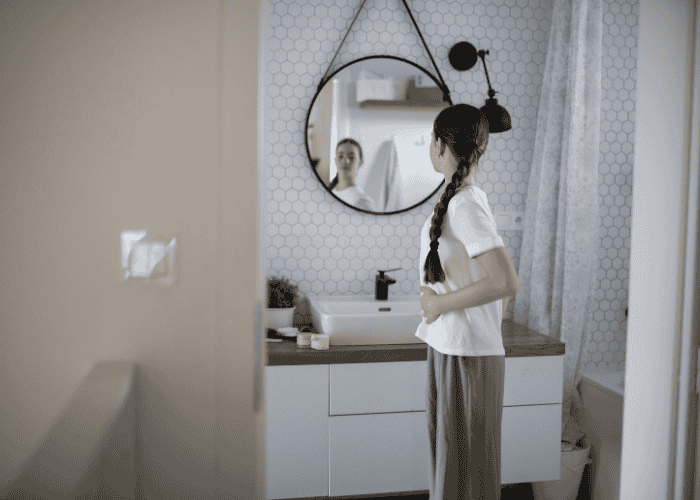 Teenage girl looking in the mirror unhappy due to body dysmorphia in teens