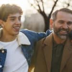 Father and son smiling outdoors with jackets on