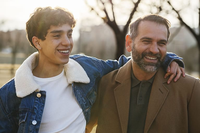 Father and son smiling outdoors with jackets on