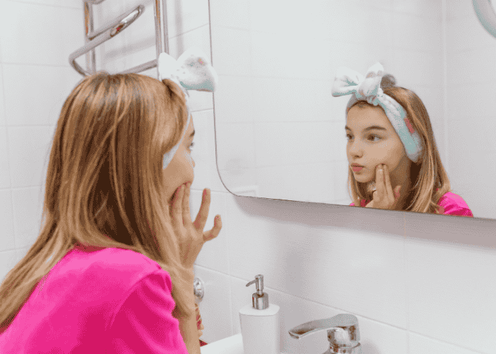 Teenage girl looking at herself in the mirror, representing identity in teens