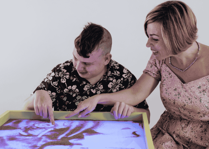 Neurodivergent teenager playing with sand during sensory-aware therapy for neurodivergent teens