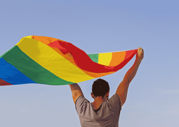 Teen boy holding Pride flag after support with support networks for LGBTQ+ teens