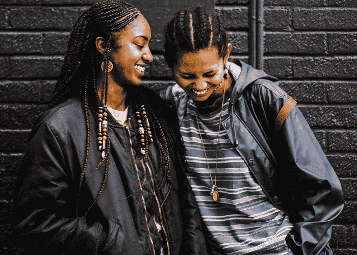 LGBTQ+ teen couple outside by wall needing support with social support networks for LGBTQ+ teens