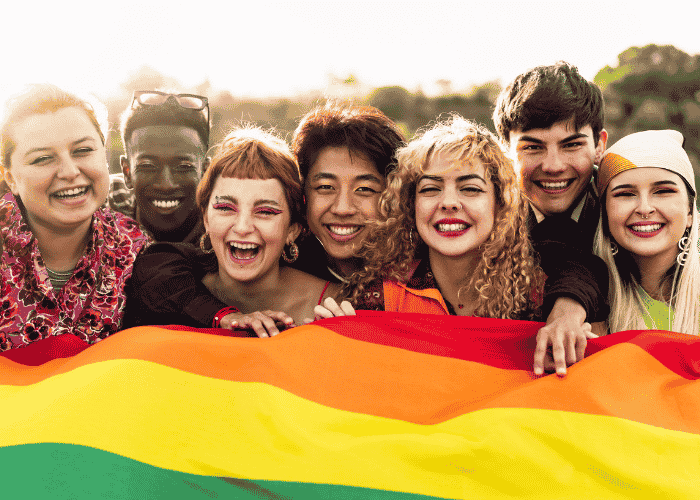 Teens holding Pride flag smiling after support with school safety for LGBTQ+ teens