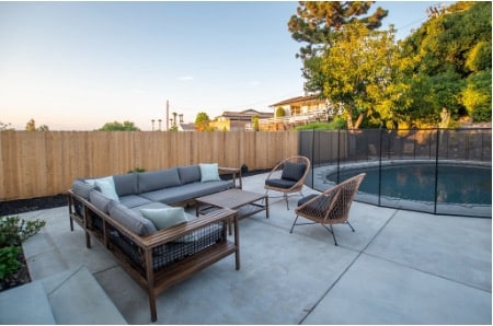 Calm backyard patio with sectional seating beside a safety-fenced pool at a Mission Prep residential group home for teens.