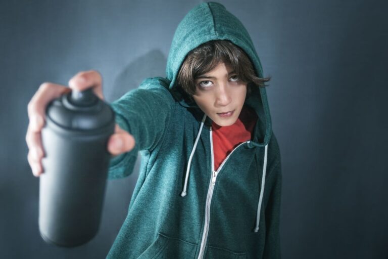 Teen wearing green hoodie holding spray paint can