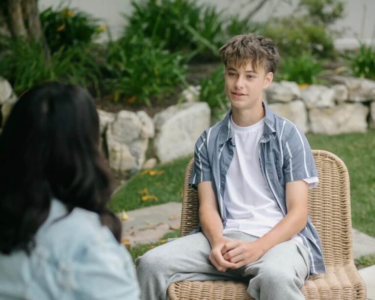 Teen boy sitting on chair outside during therapy session