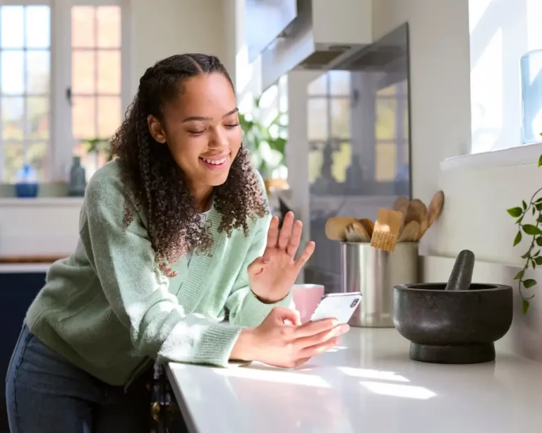 Teen girl smiling while waving to her therapist on a virtual call for IOP mental health treatment