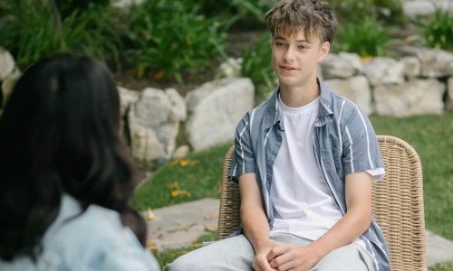 Teen boy sitting on chair outside during therapy session
